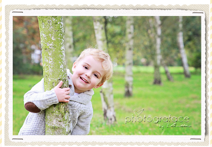 boy peeking out from a tree trunk