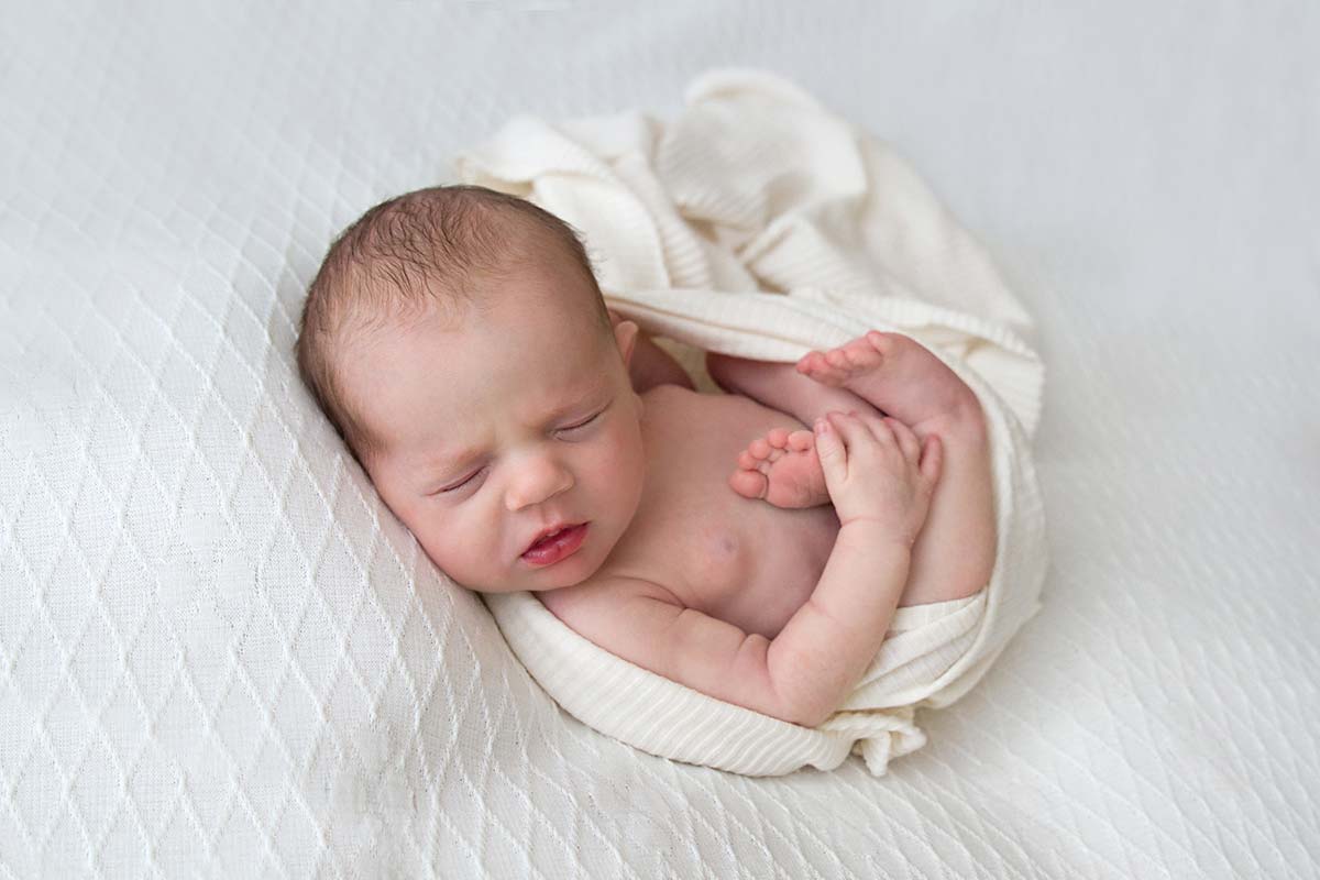 newborn baby sleeping on a white blanket